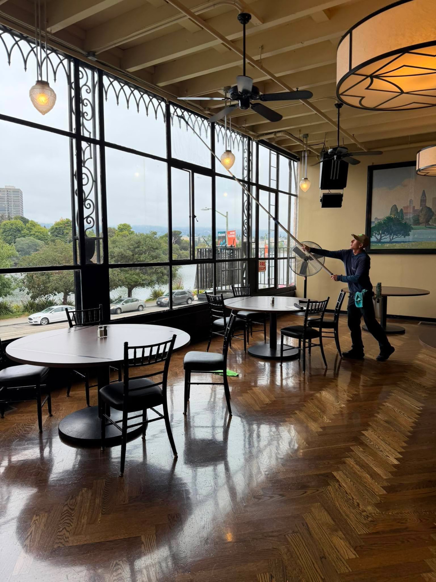 Technician cleaning tall interior windows of a commercial dining space